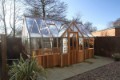 Side-angle view of Cedar Rustic T-Garden Cross Greenhouse emphasizing its distinctive cross-shaped architecture