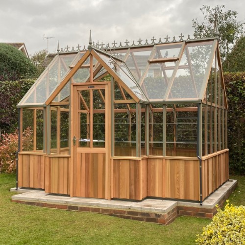 Charming evening view of illuminated Cedar Rustic T-Garden Cross Greenhouse in a tranquil garden setting