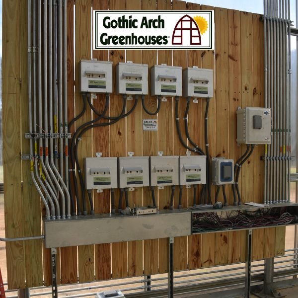 Close-up of a grower calibrating a digital thermostat sensor on a greenhouse environmental control panel